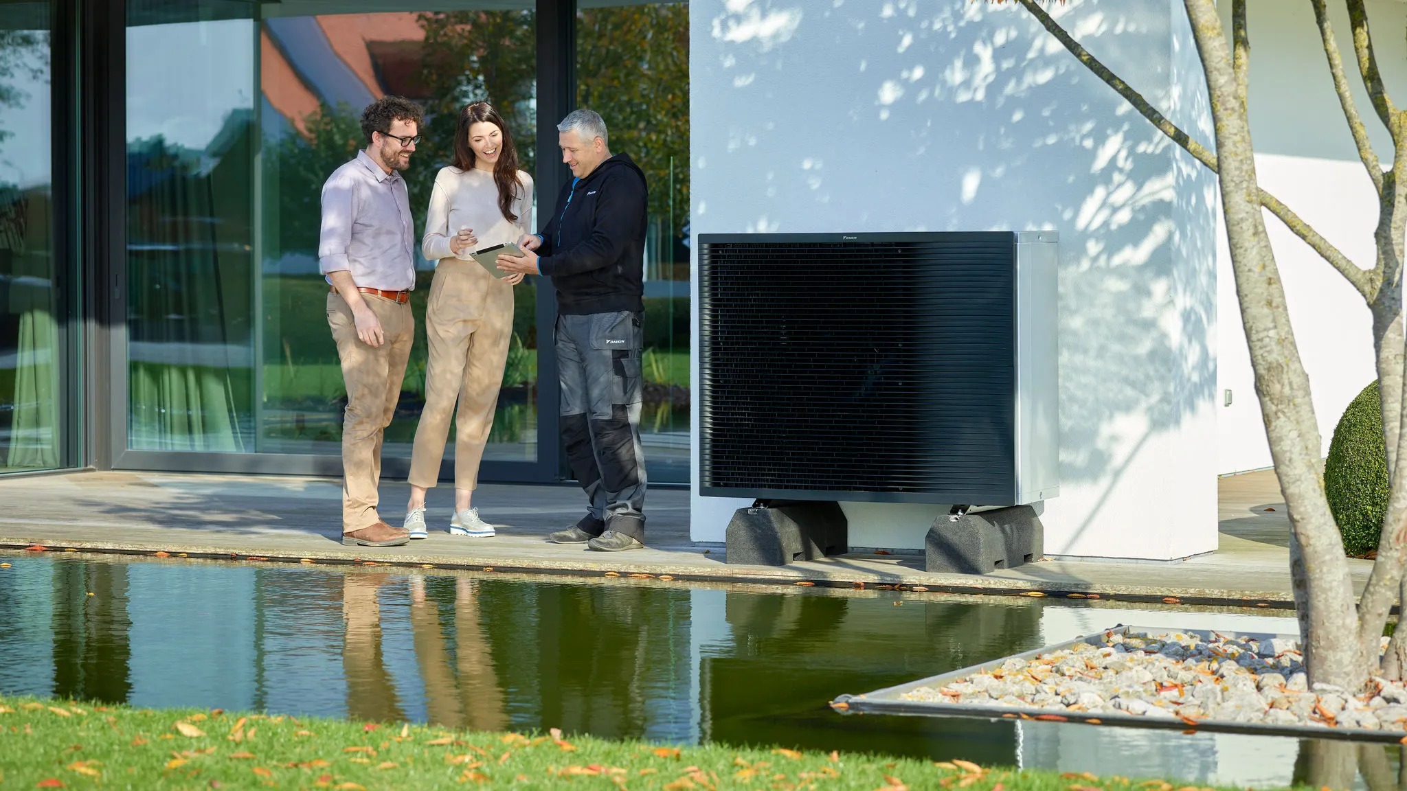 Installateur Daikin échangeant avec des clients près d'une pompe à chaleur air-eau